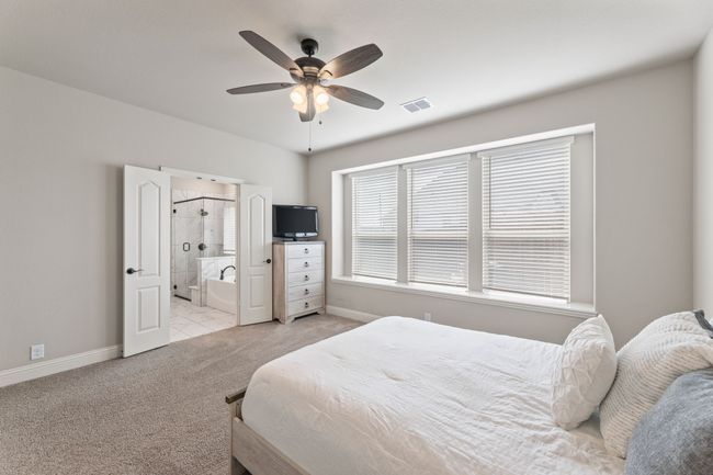 Bedroom featuring light colored carpet, ceiling fan, and ensuite bathroom | Image 15