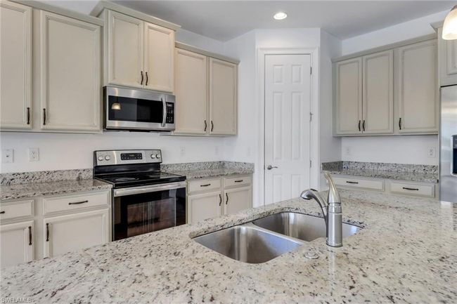 Kitchen with appliances with stainless steel finishes, a sink, recessed lighting, and light stone counters | Image 25