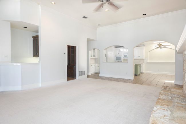 Unfurnished living room featuring arched walkways, ceiling fan, and visible vents | Image 8