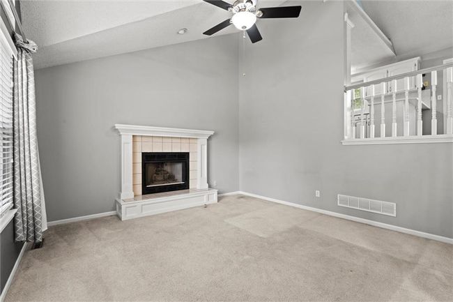 Unfurnished living room with carpet flooring, a ceiling fan, and a fireplace | Image 4