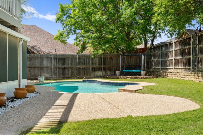 View of swimming pool featuring a patio, a fenced backyard, and a yard | Image 34