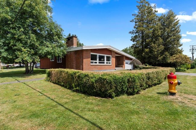 View of home's exterior with a chimney, a yard, brick siding, and an attached garage | Image 4
