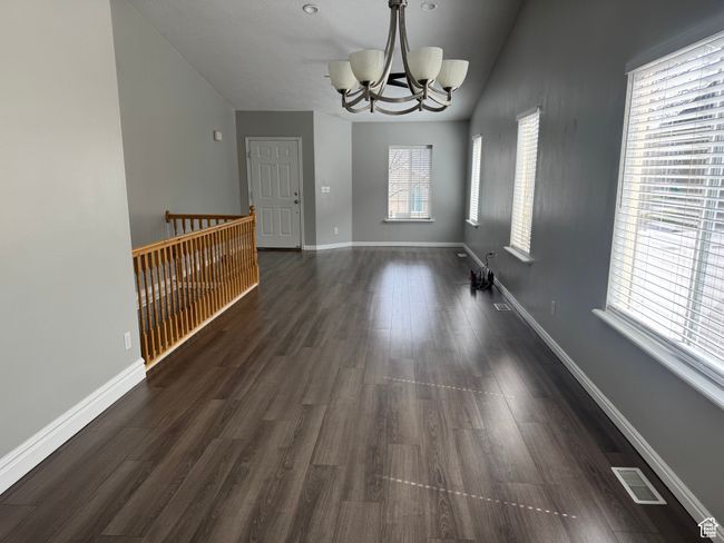 Unfurnished dining area featuring a chandelier, baseboards, dark wood-style flooring, and vaulted ceiling | Image 6