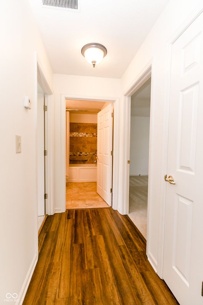 hall featuring wood finished floors and visible vents | Image 13