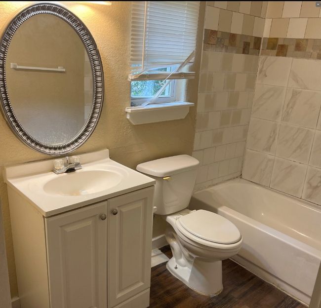 Full bathroom with a textured wall, wood finished floors, toilet, vanity, and shower / tub combination | Image 6