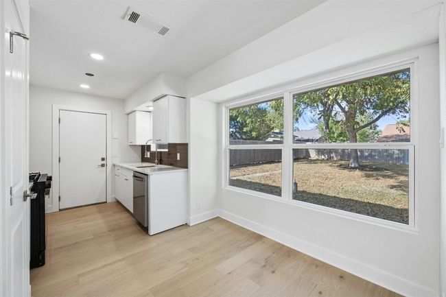 Kitchen featuring light countertops, light wood finished floors, healthy amount of natural light, white cabinets, and recessed lighting | Image 13