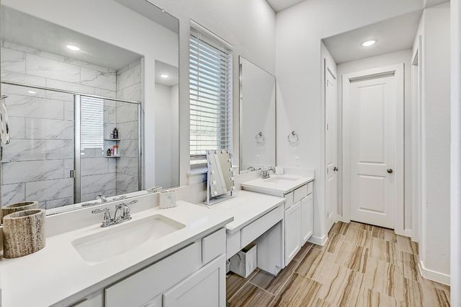 Relax in the spa-like en-suite bathroom featuring a tiered dual vanity with a quartz countertop for a touch of luxury. | Image 14