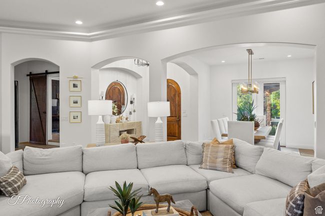 Living area with a chandelier, recessed lighting, arched walkways, and a barn door | Image 25