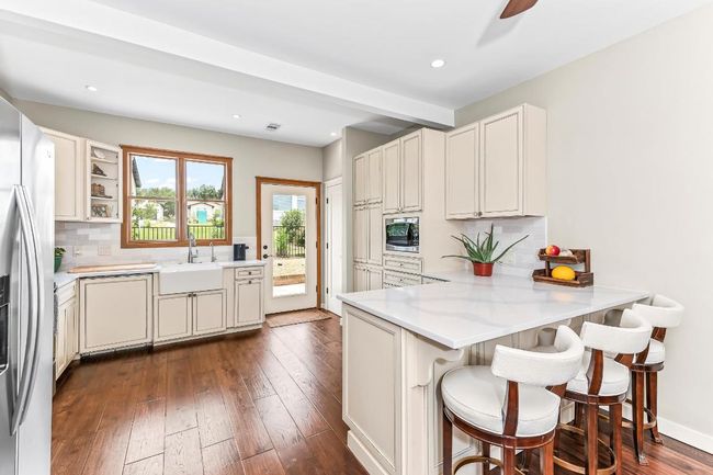 Kitchen featuring a sink, stainless steel appliances, decorative backsplash, a peninsula, and a kitchen breakfast bar | Image 8