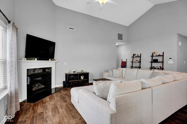 living area featuring a ceiling fan, wood finished floors, visible vents, and high vaulted ceiling | Image 15