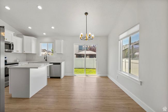 Kitchen with appliances with stainless steel finishes, light countertops, a chandelier, white cabinets, and light wood-style floors | Image 5