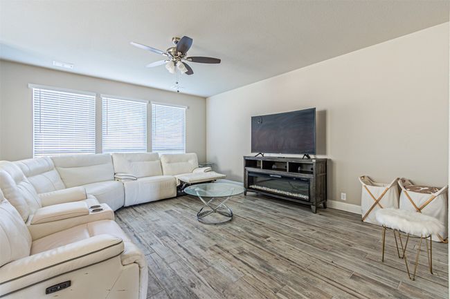 Living area with a ceiling fan, wood finished floors, and baseboards | Image 14
