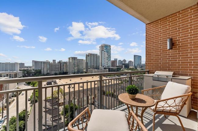 Stylish balcony with city views, featuring comfortable seating and a built-in grill, perfect for outdoor relaxation and entertaining. | Image 20