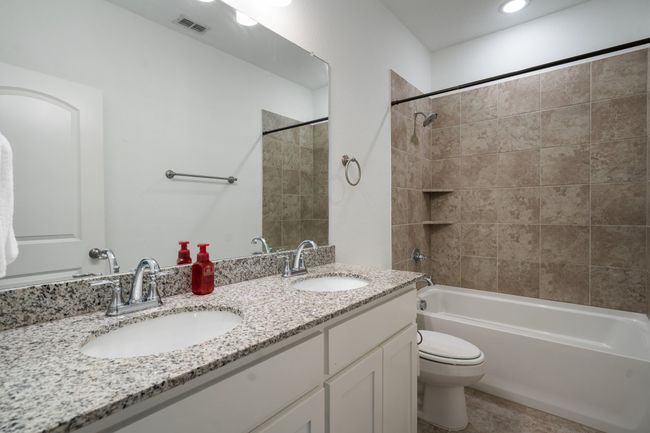 Full bath with toilet, double vanity, bathing tub / shower combination, and tile patterned floors | Image 13