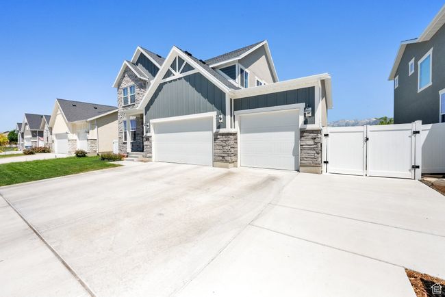 View of front of home featuring a gate, board and batten siding, stone siding, an attached garage, and driveway | Image 4