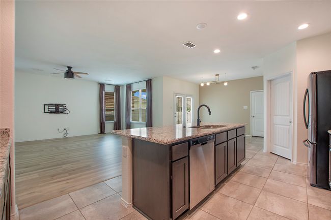 Kitchen featuring stainless steel appliances, light tile patterned flooring, open floor plan, a ceiling fan, and a center island with sink | Image 15