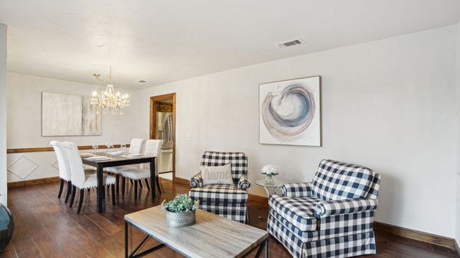 Dining area featuring a notable chandelier, visible vents, baseboards, and dark wood-style flooring | Image 6