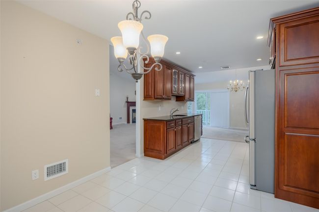 Kitchen with a chandelier, stainless steel appliances, dark countertops, recessed lighting, and glass insert cabinets | Image 14