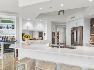 Kitchen featuring kitchen peninsula, wine cooler, a kitchen bar, white cabinets, and appliances with stainless steel finishes | Image 3