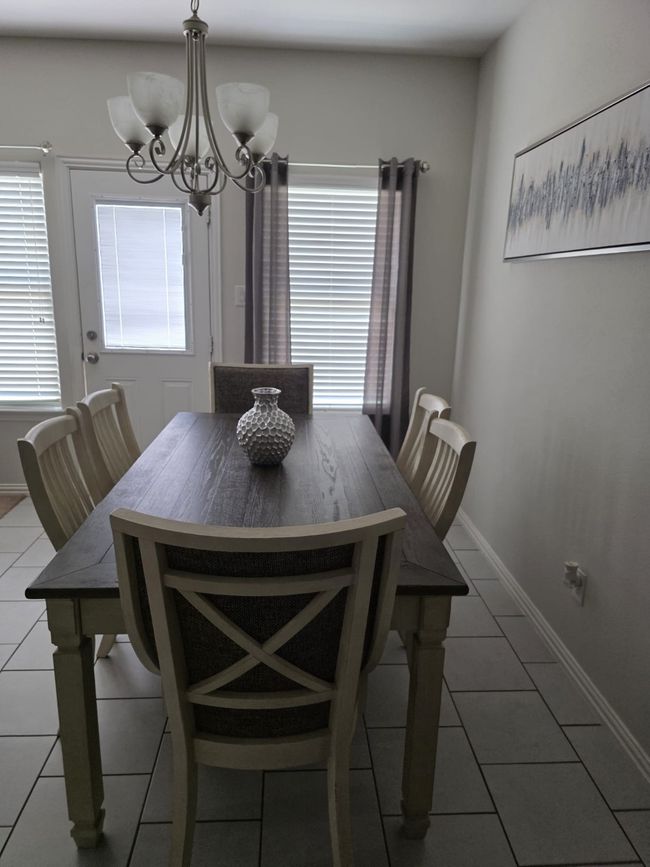 Tiled dining area featuring a chandelier and baseboards | Image 5