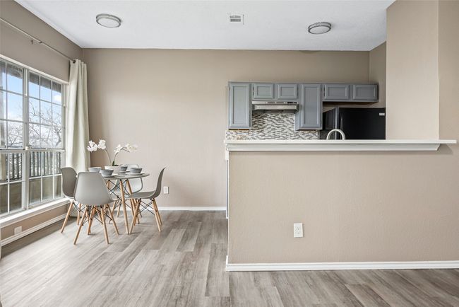 Kitchen featuring gray cabinets, black fridge, light hardwood / wood-style floors, and decorative backsplash | Image 10