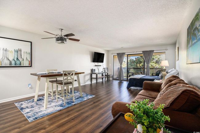 Living room with a textured ceiling, dark wood-style flooring, and ceiling fan | Image 16
