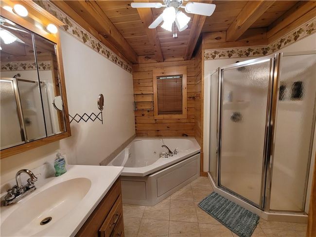 Bathroom featuring tile floors, ceiling fan, wood ceiling, and plus walk in shower | Image 9