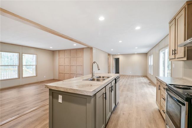 Kitchen with a sink, stainless steel appliances, a center island with sink, light wood-style flooring, and open floor plan | Image 10