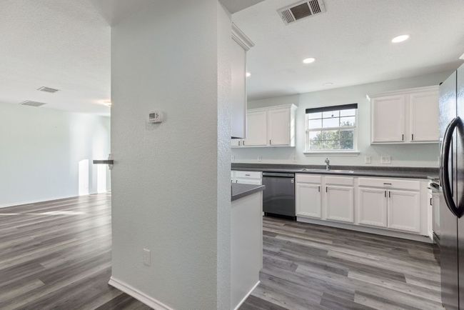 Kitchen featuring dishwasher, a sink, white cabinets, dark countertops, and Grey wood-style vinyl floors | Image 16