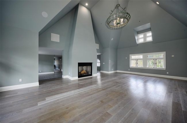 Unfurnished living room featuring visible vents, high vaulted ceiling, a notable chandelier, and baseboards | Image 13