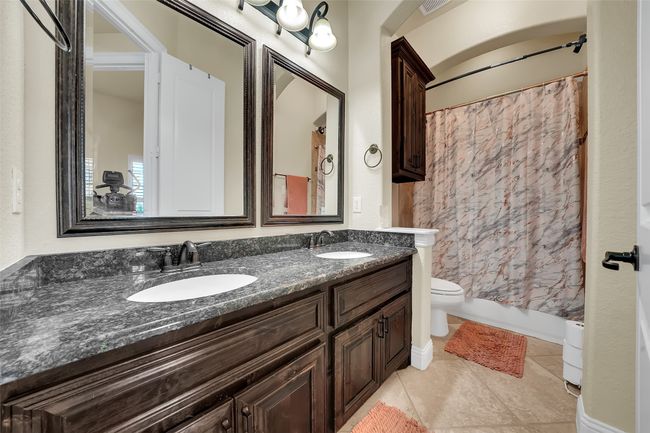 Full bath featuring shower / tub combo, double vanity, and light tile patterned flooring | Image 30