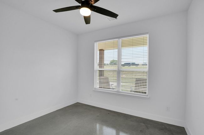 Unfurnished bedroom with multiple windows, concrete floors, and a ceiling fan | Image 24