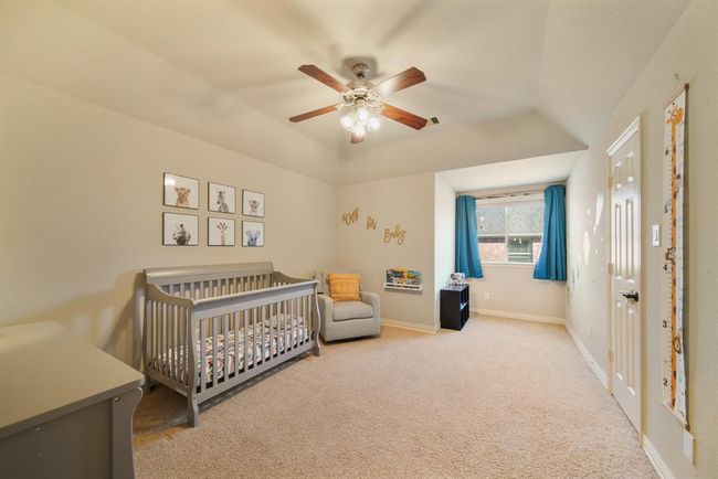 The fifth bedroom features a high ceiling with ceiling fan & lighting, window with shade, walk-in wardrobe closet & carpet. | Image 40