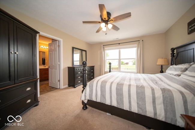 bedroom with light colored carpet, ensuite bath, baseboards, and ceiling fan | Image 17