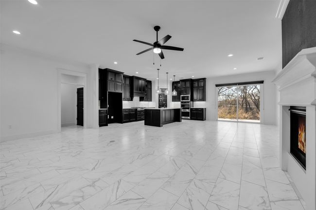Living area with marble finish floor, a warm lit fireplace, recessed lighting, and ceiling fan | Image 6