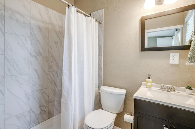 Bathroom with vanity, a shower with shower curtain, and a textured wall | Image 16