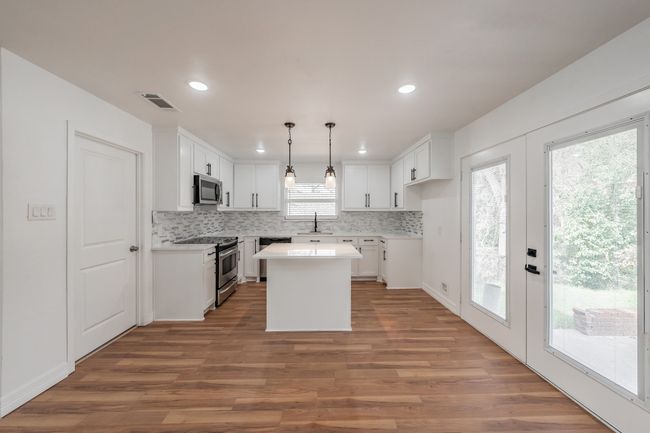 Kitchen featuring appliances with stainless steel finishes, a sink, wood finished floors, decorative backsplash, and recessed lighting | Image 39