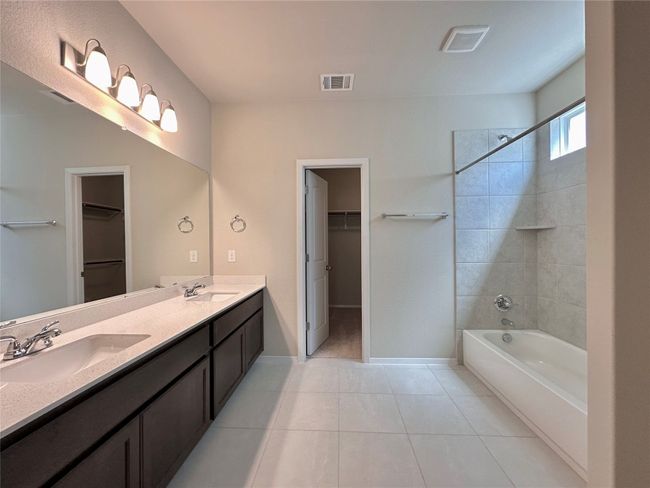 Bathroom with double vanity, washtub / shower combination, a walk in closet, and tile patterned floors | Image 12