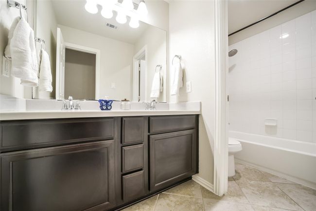 Across the hall is the secondary full bathroom. With double sinks and a privacy door separating the toilet and shower, this bathroom is functional for multiple family members and guests. | Image 23