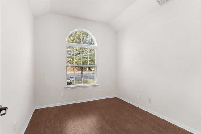 Spare room featuring vaulted ceiling, baseboards, dark wood-style flooring, and visible vents | Image 6