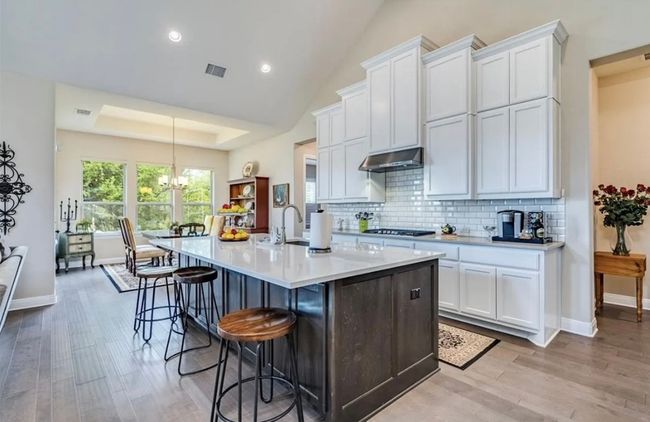 Open kitchen looking into the living and dining areas with built in cabinets underneath bar seating area | Image 4