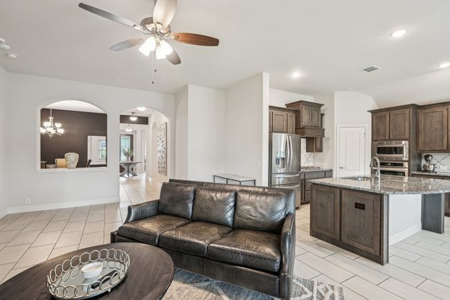 Living room with arched walkways, a ceiling fan, recessed lighting, light tile patterned floors, open to kitchen plus breakfast | Image 12