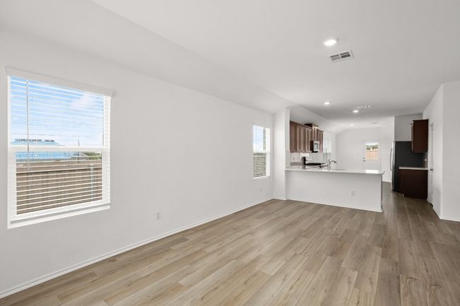 Unfurnished living room with light wood-style floors, a sink, healthy amount of natural light, recessed lighting, and lofted ceiling | Image 4
