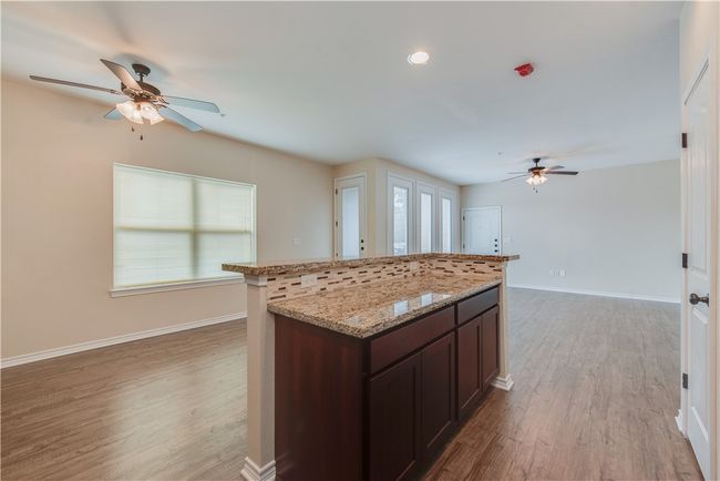 Kitchen featuring a center island, light wood-style flooring, baseboards, and ceiling fan | Image 5
