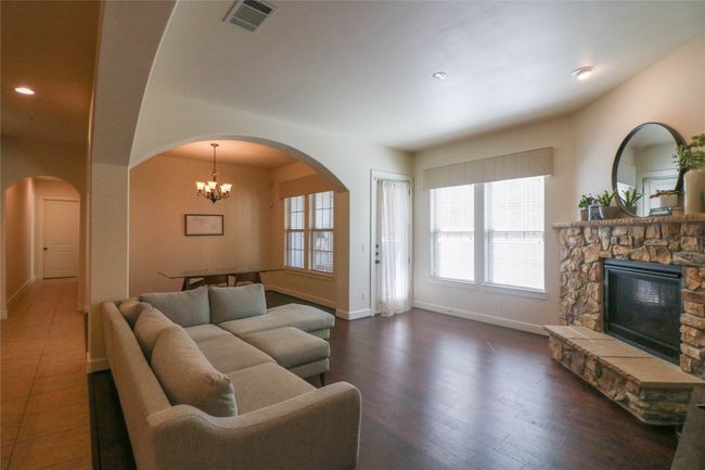 Living area featuring a fireplace, arched walkways, visible vents, and a chandelier | Image 4