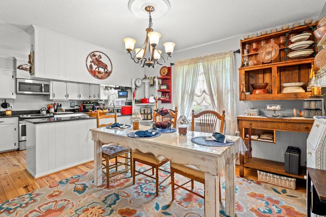 Dining space with light wood finished floors, a chandelier, a textured ceiling, and crown molding | Image 5