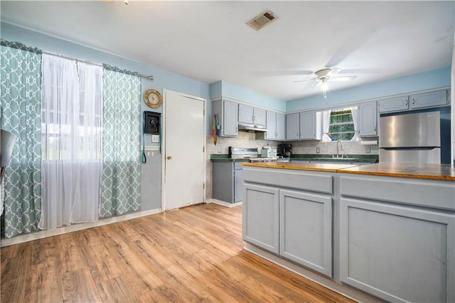 Kitchen featuring stainless steel fridge, wooden counters, gray cabinets, a ceiling fan, and visible vents | Image 11