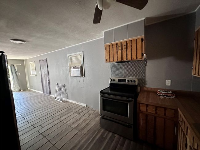 Kitchen featuring stainless steel electric range, a ceiling fan, a textured ceiling, dark wood finished floors, and dark countertops | Image 7