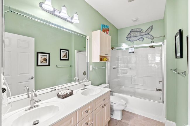 Bathroom with double vanity, tile patterned flooring, and combined bath / shower with glass door | Image 9