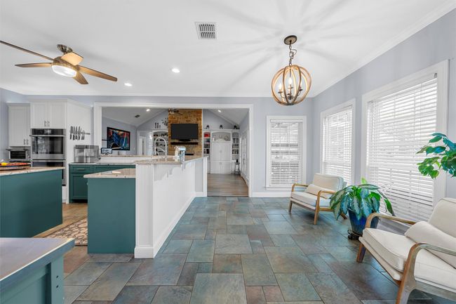 Kitchen with open floor plan, a peninsula, visible vents, double oven, and ceiling fan with notable chandelier | Image 14